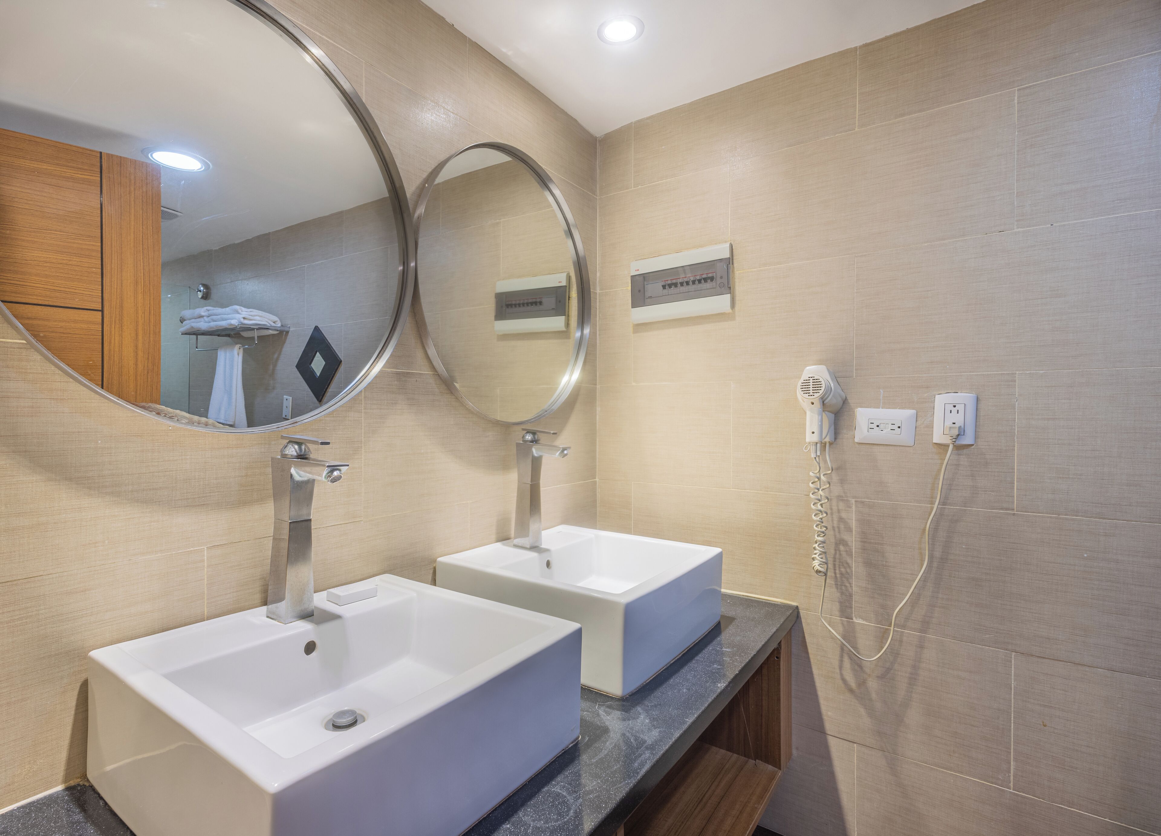 A modern bathroom with two sinks, a hairdryer, and a mirror.