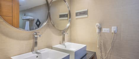 A modern bathroom with two sinks, a hairdryer, and a mirror.