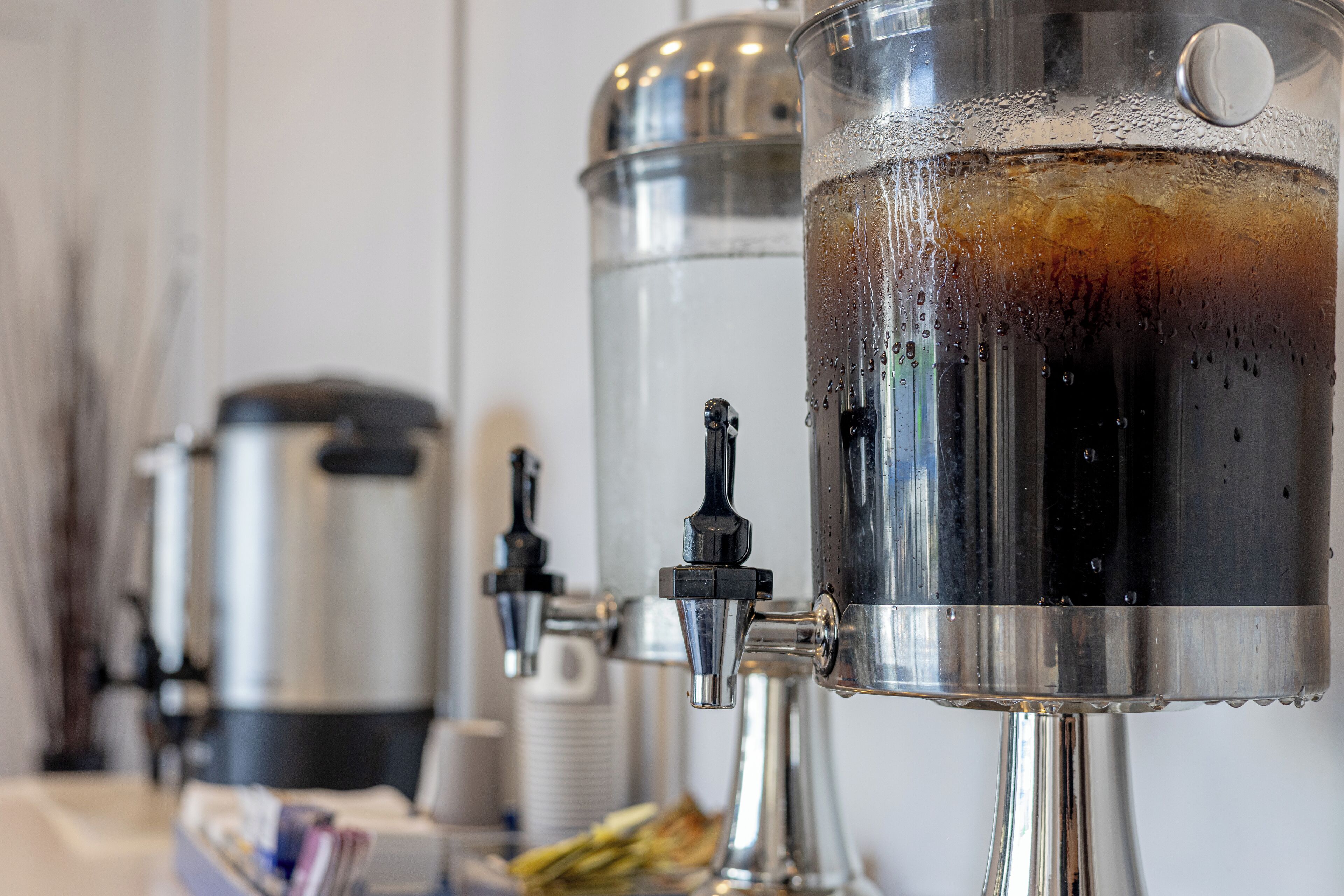 Una máquina de café con varios dispensadores, un dispensador de agua y una cafetera al fondo.