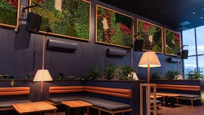 Un interior moderno con zonas de estar, una mesa de madera y un altavoz de pared.