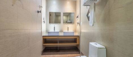 A modern bathroom with two sinks, a mirror, and a toilet.