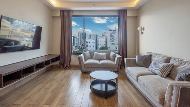 Una sala de estar moderna con un ventanal grande, un sofá, una mesa de centro y un televisor en la pared.