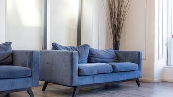 A modern living room with two grey sofas and a tall vase of branches.