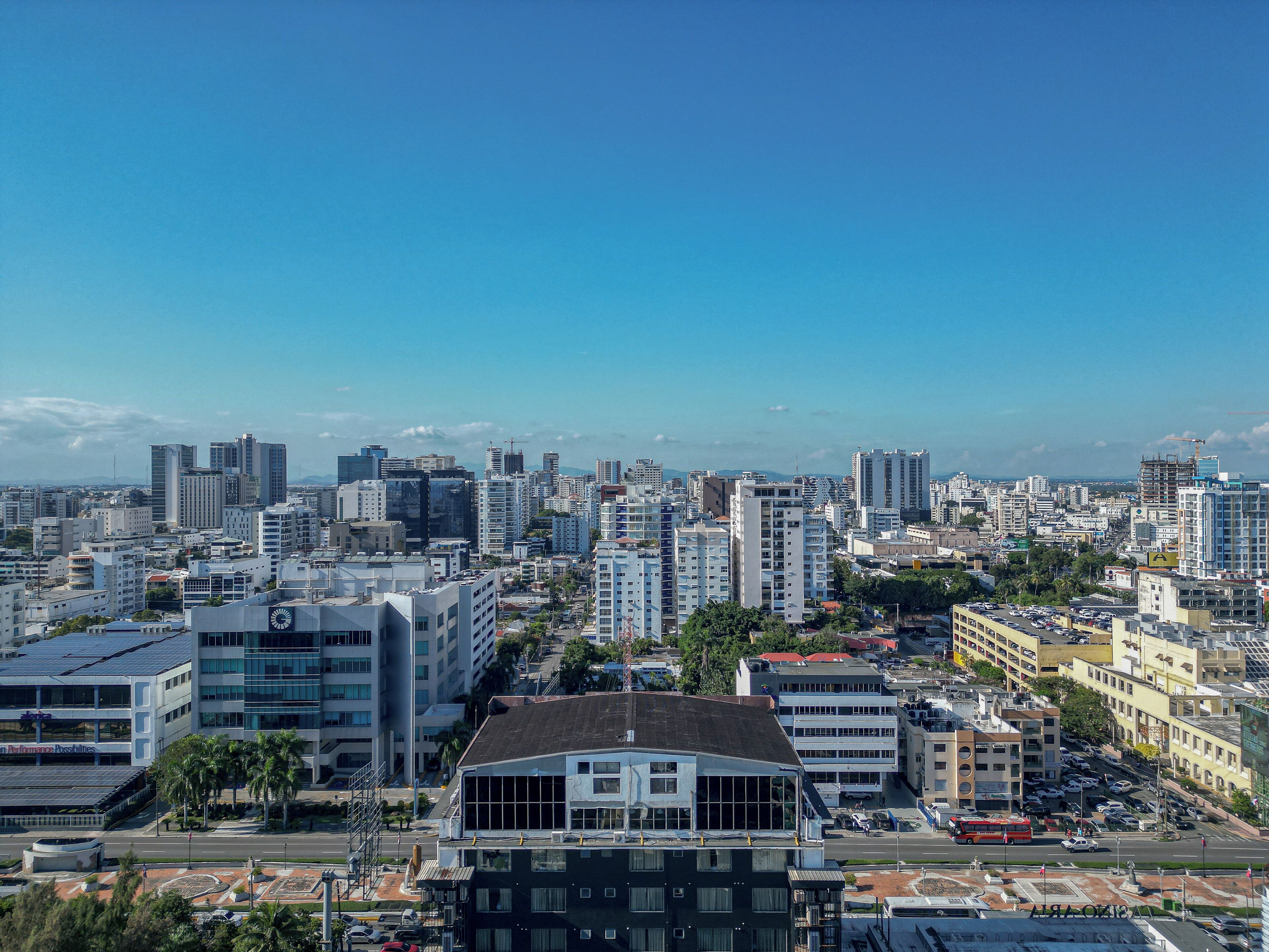 A cityscape with modern high-rise buildings, a mix of commercial and residential structures, and a clear blue sky.