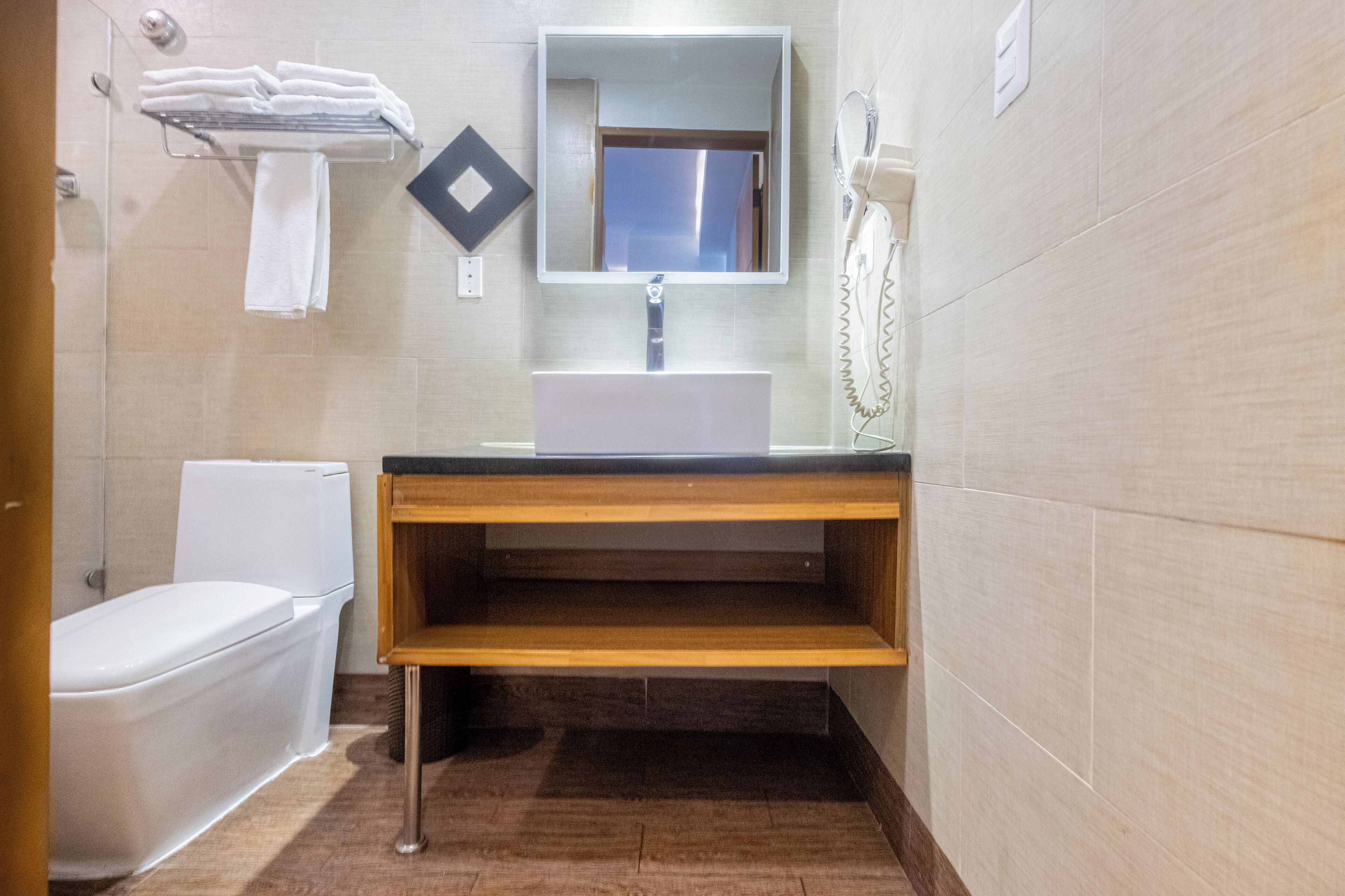A bathroom with a white sink, a mirror, a towel rack, and a toilet.