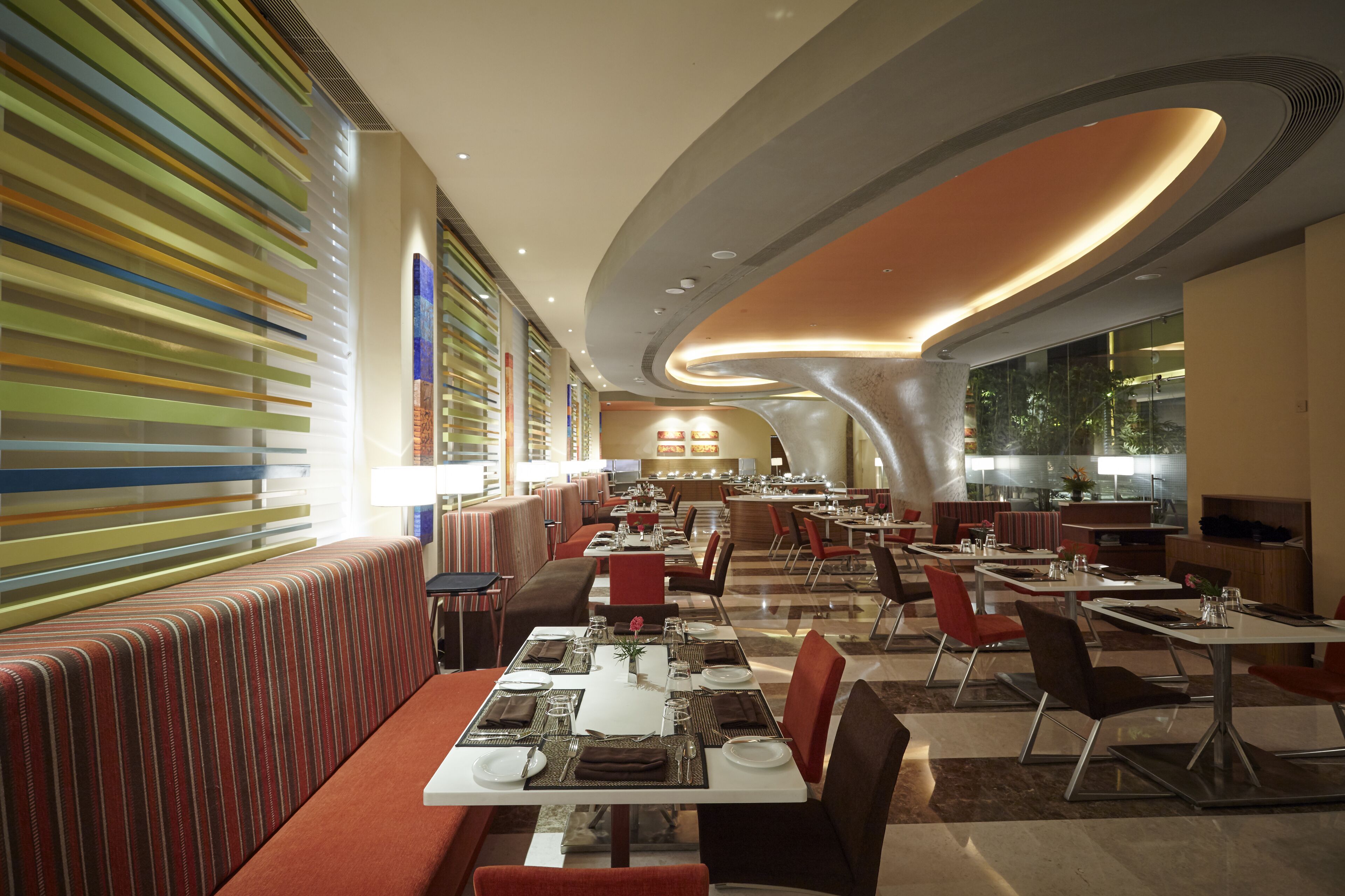 A modern restaurant with striped seating, a central bar, and a curved ceiling.