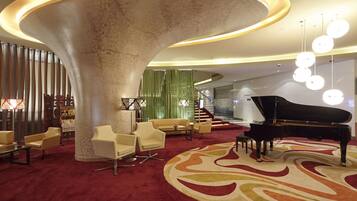 A spacious lobby with a grand piano, comfortable seating, and a distinctive circular column.