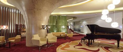 A spacious lobby with a grand piano, comfortable seating, and a distinctive circular column.