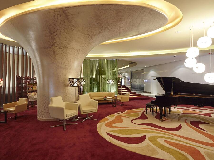 A spacious lobby with a grand piano, comfortable seating, and a distinctive circular column.