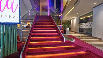 Eine Treppe mit rotem Teppich und beleuchteten Stufen, die zu einer höheren Etage in einem modernen Gebäude führt.