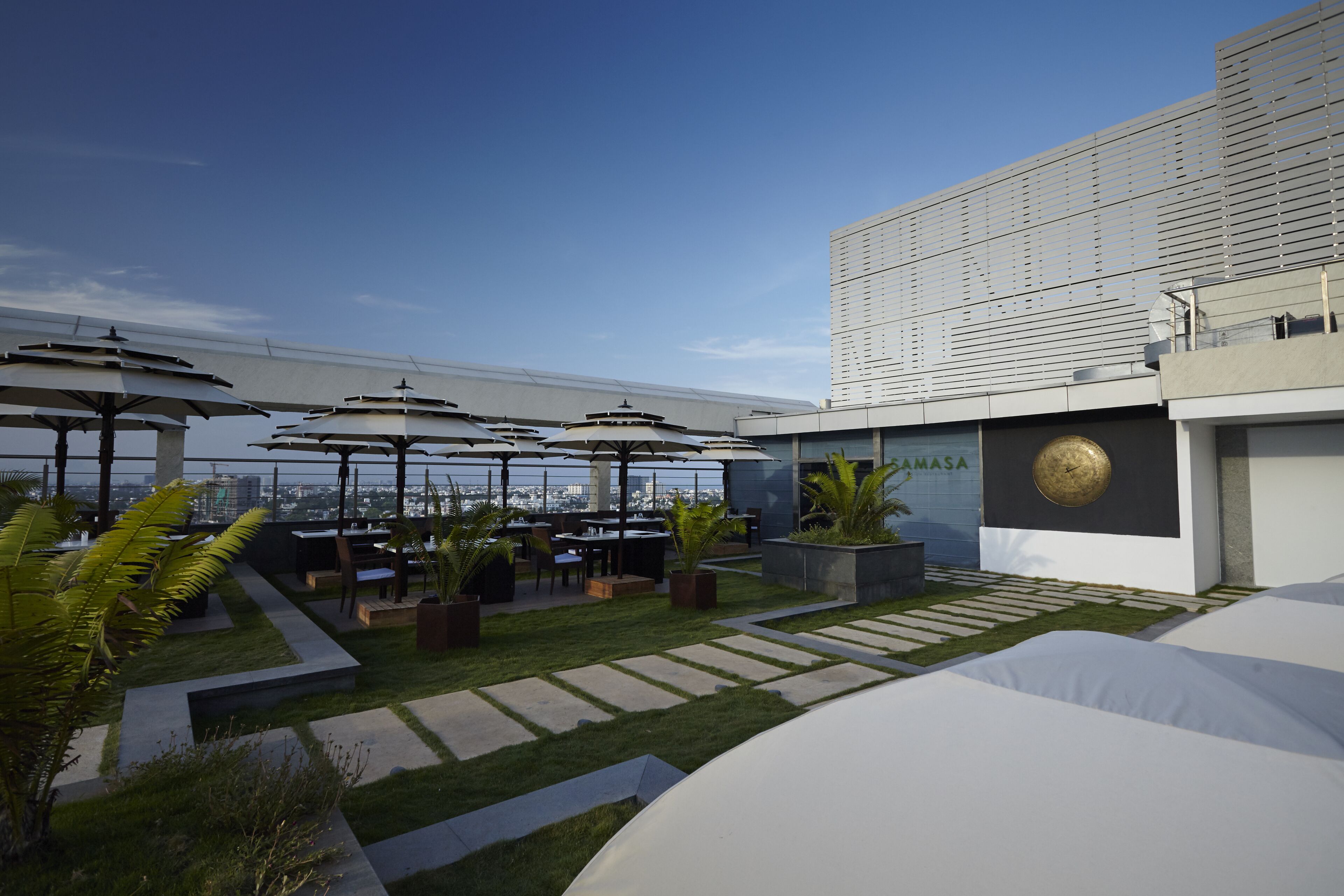 Terraço no telhado com área de estar externa, plantas em vasos e vista para o horizonte urbano.