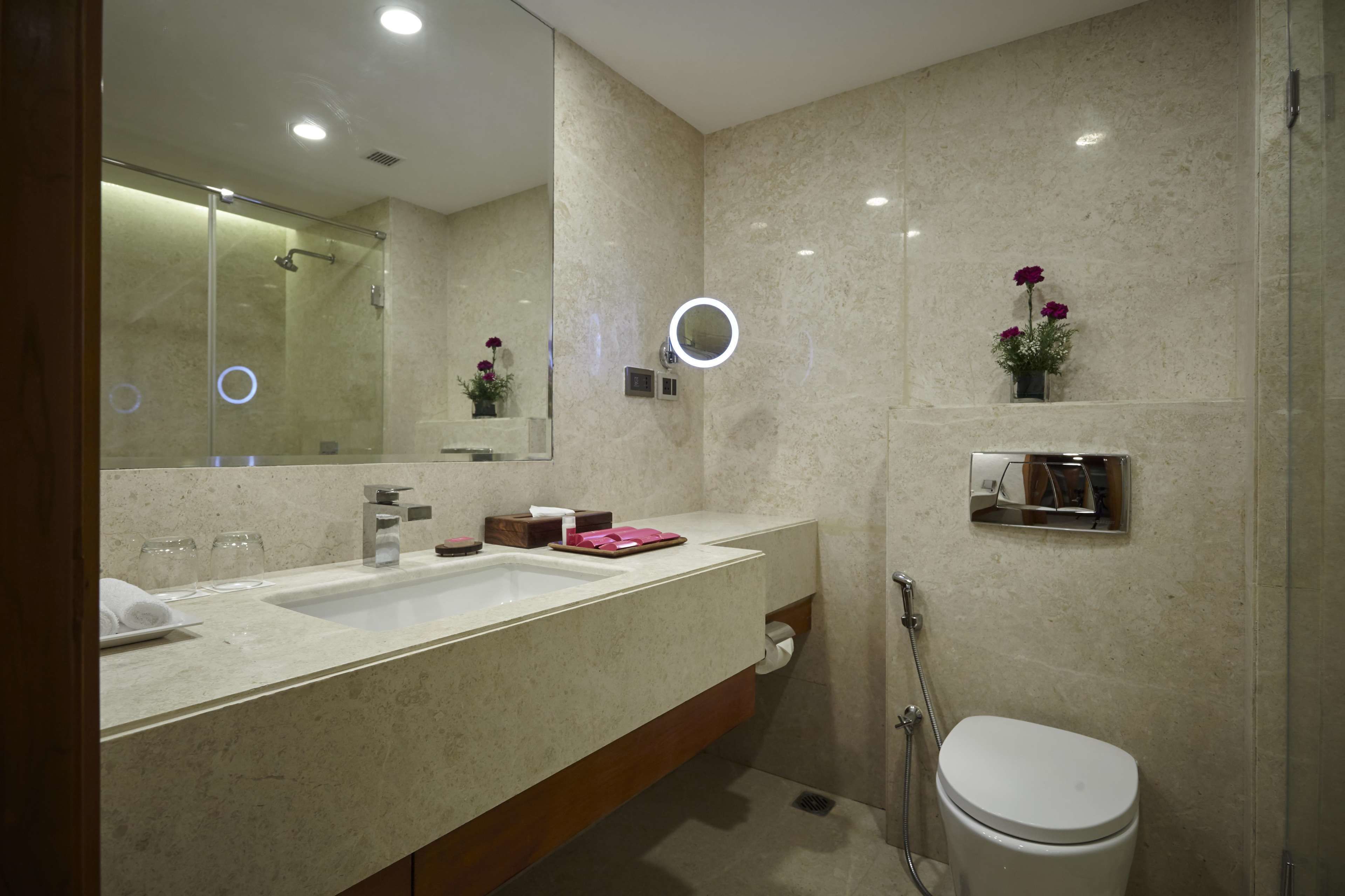 Un baño moderno con un espejo grande, dos lavamanos, un inodoro y una ducha.