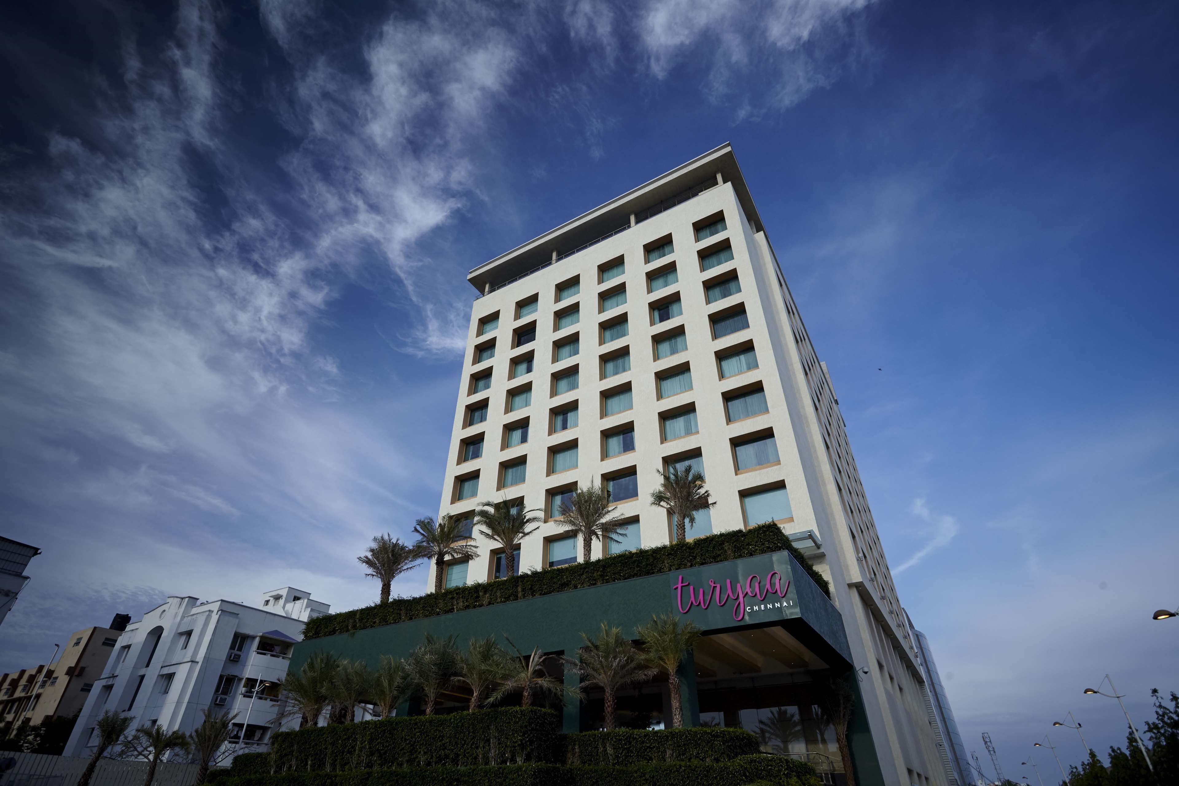 A tall hotel with a modern design, featuring a prominent entrance and a clear sky in the background.