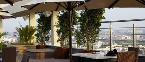 A rooftop terrace with outdoor seating, umbrellas, and potted plants.
