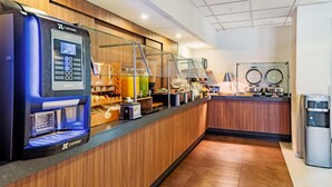 Una estación de café autoservicio con una máquina de café, un expositor de vidrio y una variedad de alimentos.