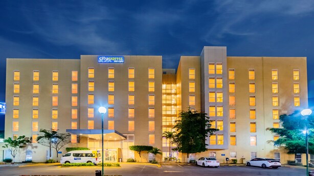 Un hotel con diseño moderno, que destaca el letrero 'CityExpress', varios pisos y una entrada bien iluminada.