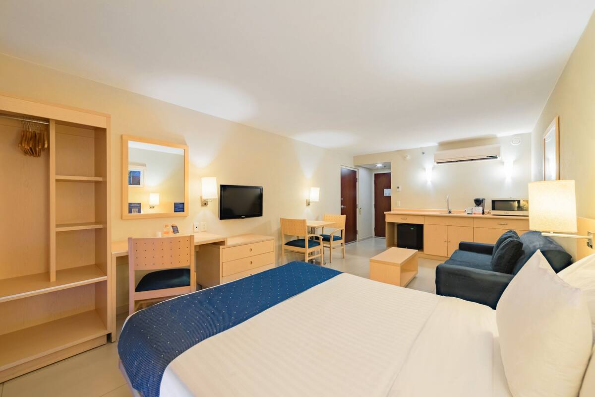 Ein Hotelzimmer mit Bett, Schreibtisch, Stuhl, Kleiderschrank und Fernseher.