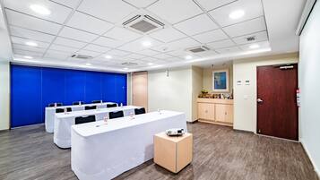 A conference room with a long table, chairs, a projector, and a blue partition wall.