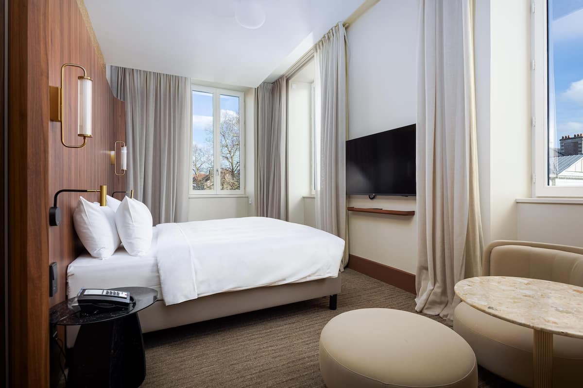 Habitación de hotel con cama, televisión, una mesita y una silla.