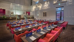 A conference room with multiple tables and chairs, a staircase, and decorative wall panels. - Radisson Blu Hotel Nantes (Nantes)