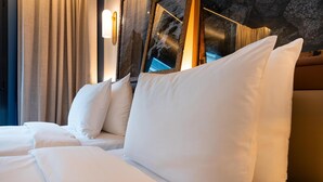 A hotel room with a bed, pillows, a headboard, curtains, and a wall with a textured surface. - Radisson Blu Hotel Nantes (Nantes)