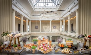 A luxurious atrium with high ceilings, classical columns, and a central glass floor.