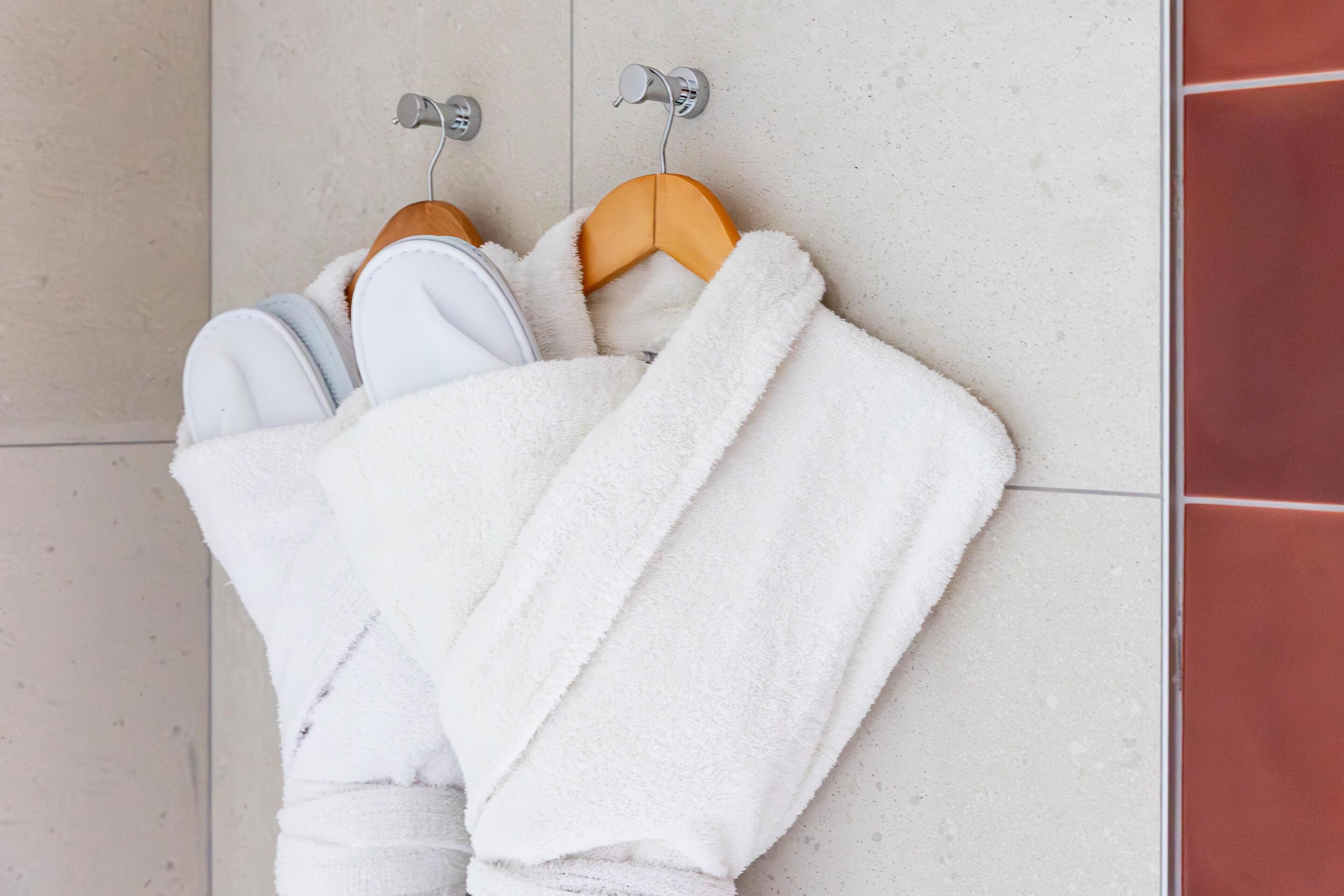 A bathroom with a tiled floor, a white towel, and a wooden hanger.