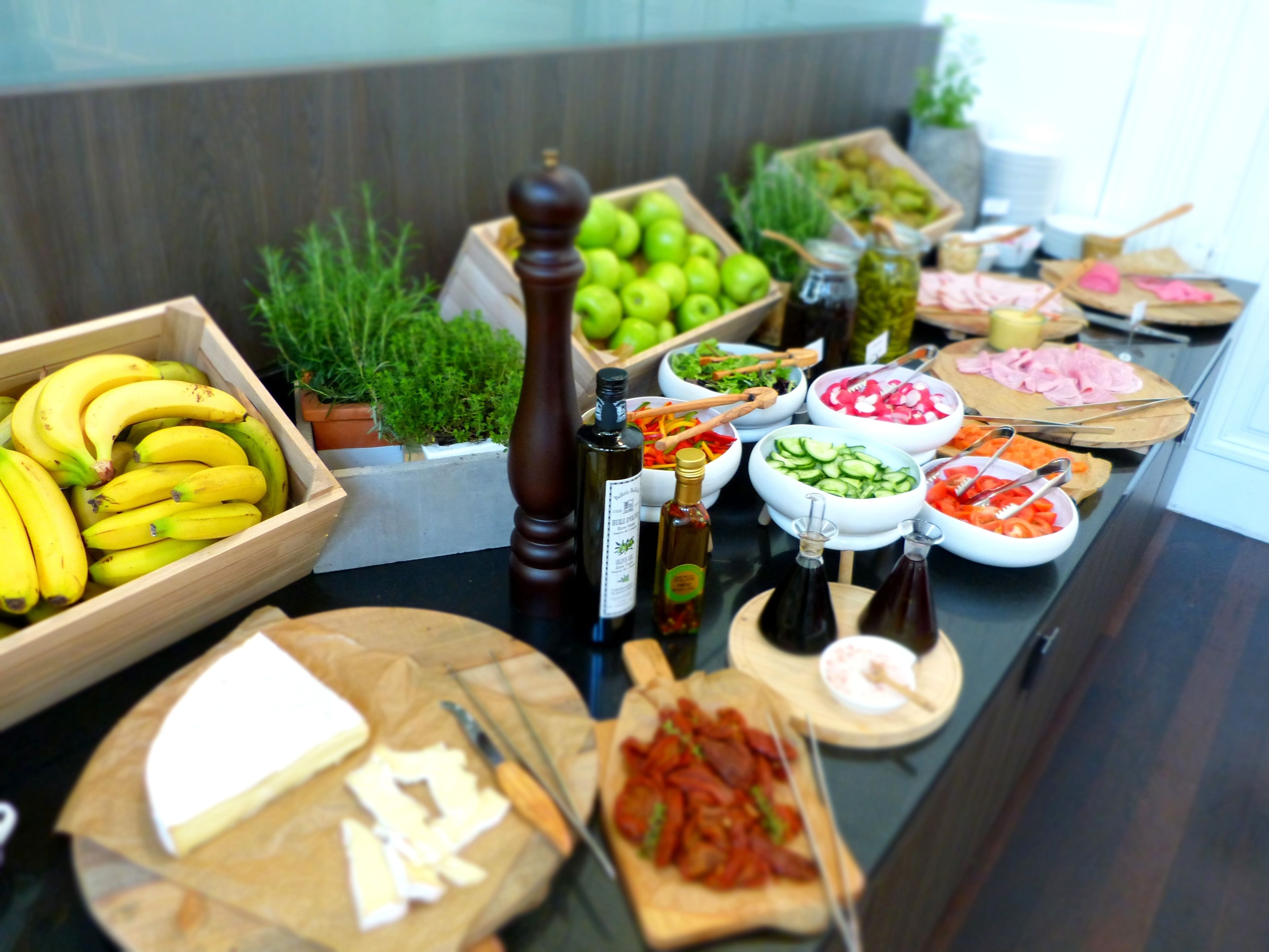 A buffet table with various food items including bananas, salads, and meats.