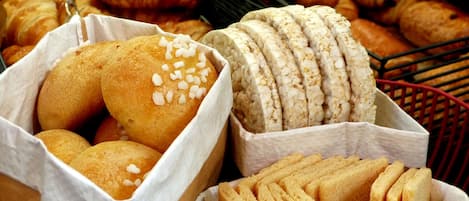 A variety of baked goods including bread rolls, croissants, and a loaf with sesame seeds.