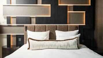 Una habitación de hotel moderna con una cama grande, un cabecero con iluminación integrada y un panel de control en la pared.