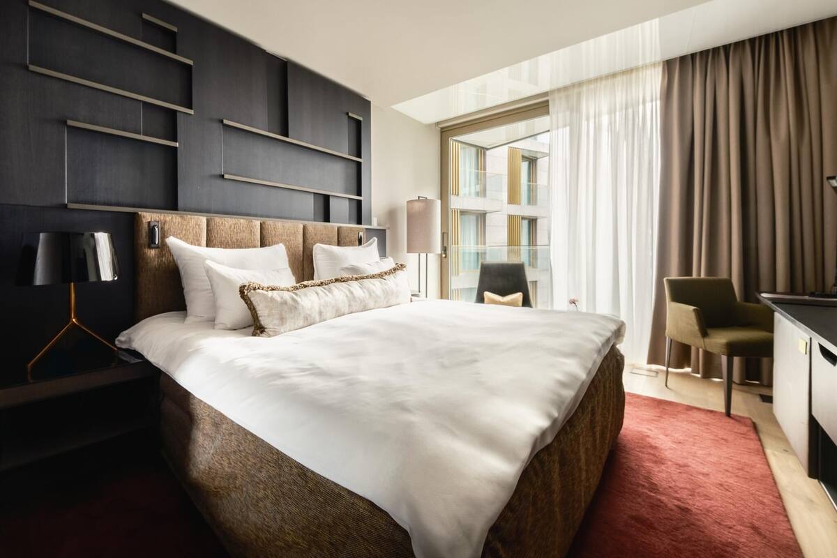 Quarto de hotel moderno com uma cama grande, uma escrivaninha e uma cadeira.