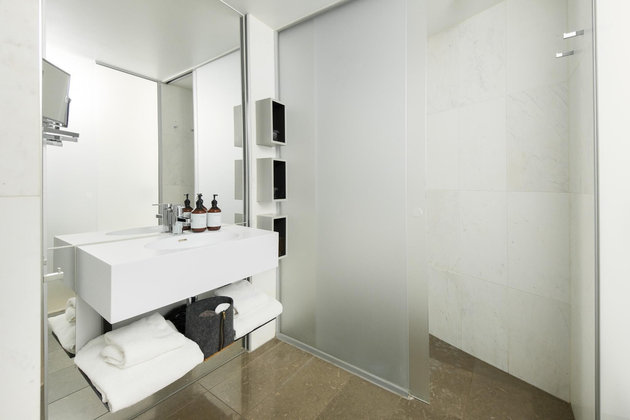 A modern bathroom with a white vanity, a glass shower enclosure, and a large mirror.