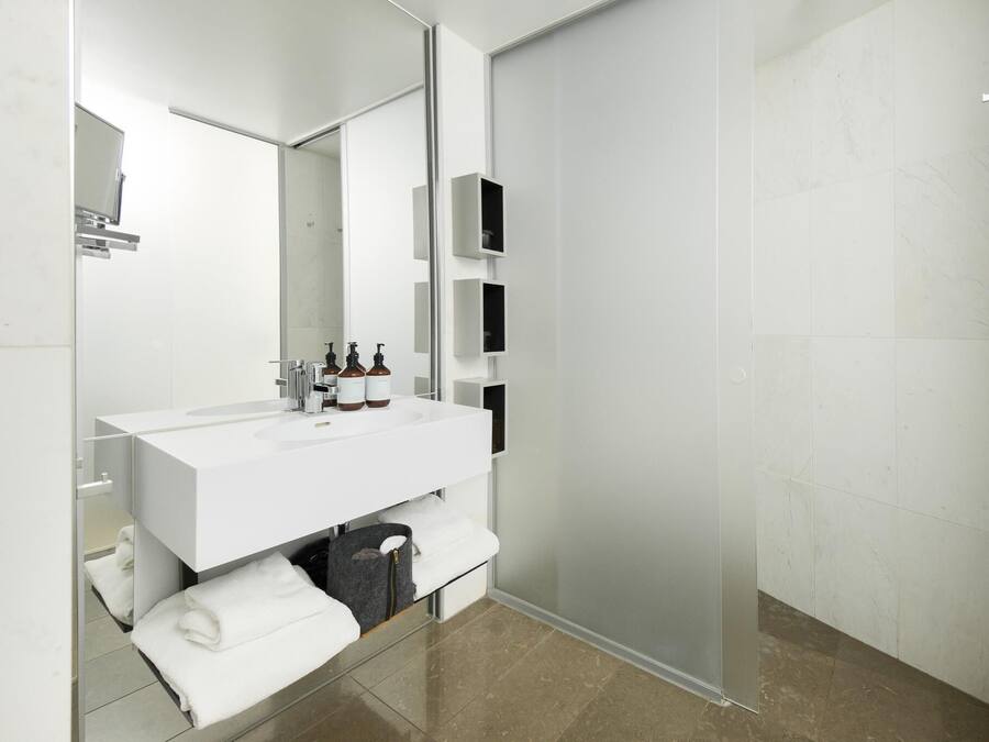 A modern bathroom with a white vanity, a glass shower enclosure, and a large mirror.