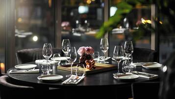 Une table à manger dressée pour un repas, avec plusieurs verres à vin, des assiettes et un centre de table.