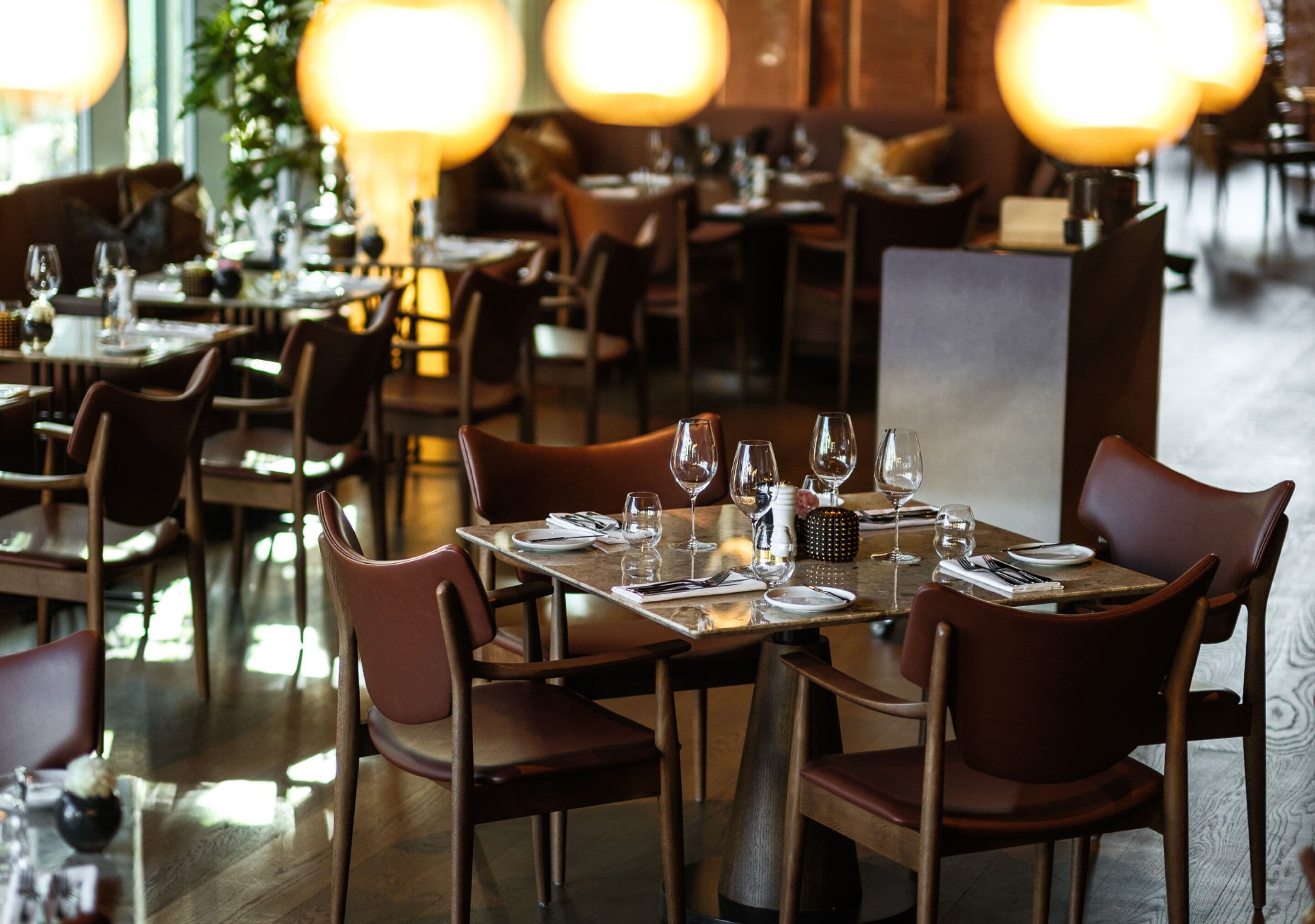 A restaurant with tables set for dining, chairs, and a warm ambiance.