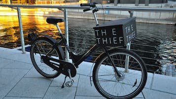 Una bicicleta estática con una canasta que dice 'THE THIEF' estacionada junto a un canal.