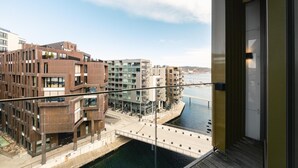 A modern building with a balcony overlooking a canal and other buildings.