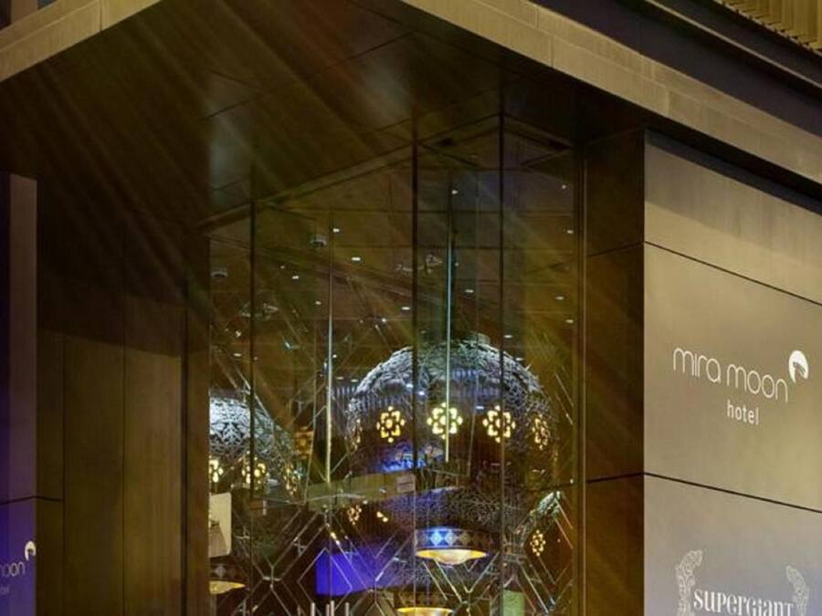 En hotellentrén med en glasfasad som reflekterar ljuset från interiören och ett dekorativt tak.