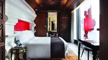 Habitación de hotel con una cama grande, una mesita de noche con teléfono, un escritorio con silla y vistas a un diseño floral rojo.