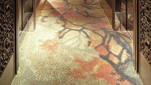 A hallway with intricate metal paneling, a patterned floor, and a large decorative light fixture.