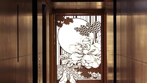 A hallway with a traditional decorative screen, a patterned carpet, and metallic walls.
