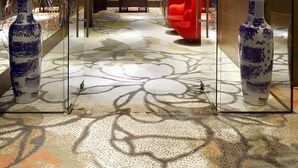 A modern interior with a geometric patterned floor, a central hanging light fixture, and two vases on display.