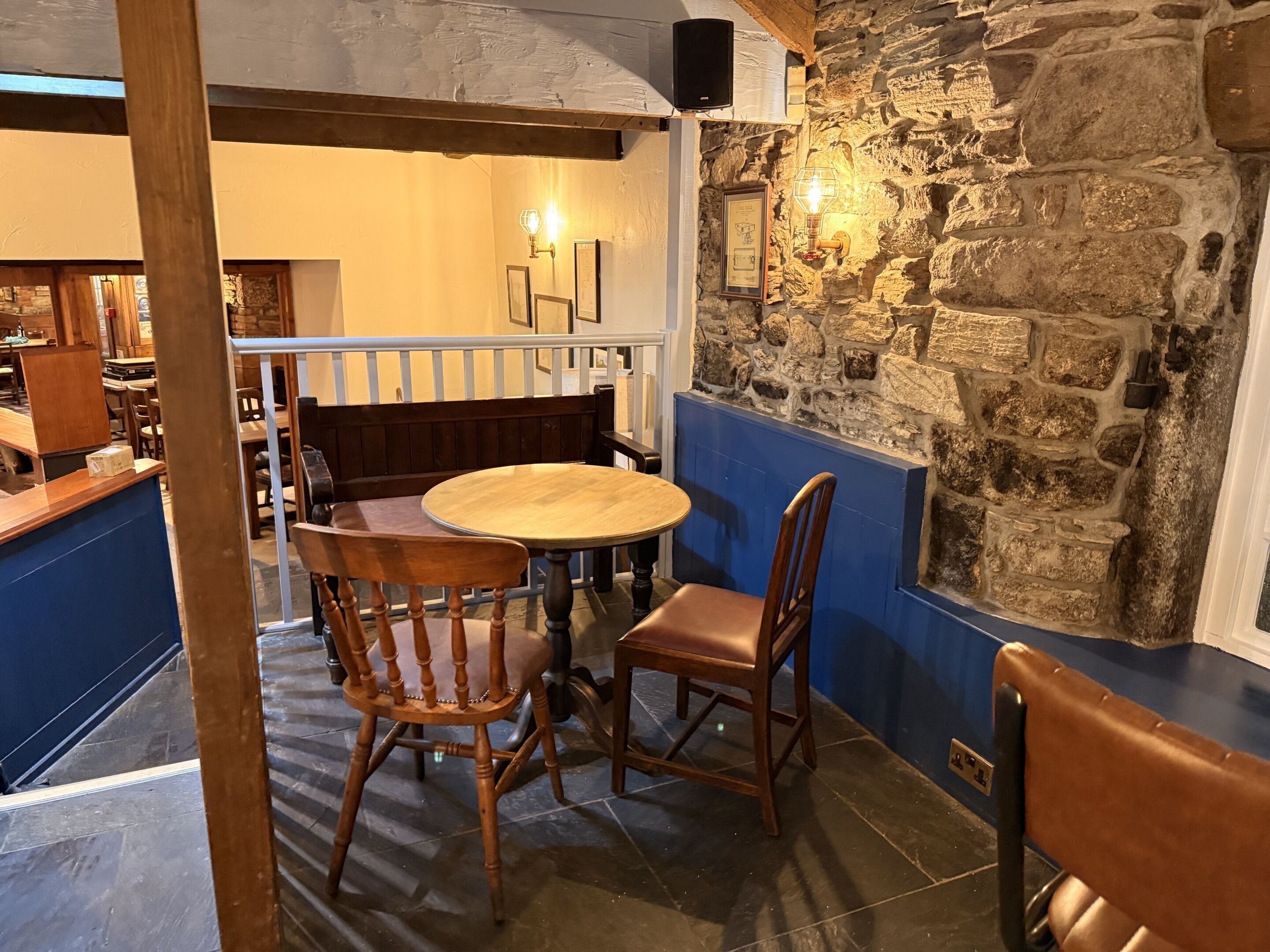 A restaurant interior with a stone wall, wooden chairs, a round table, and a blue accent wall.