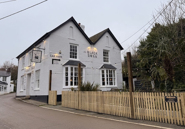 A white building with 'The Black Swan' signage, a wooden fence, and a 'Car Park' sign.