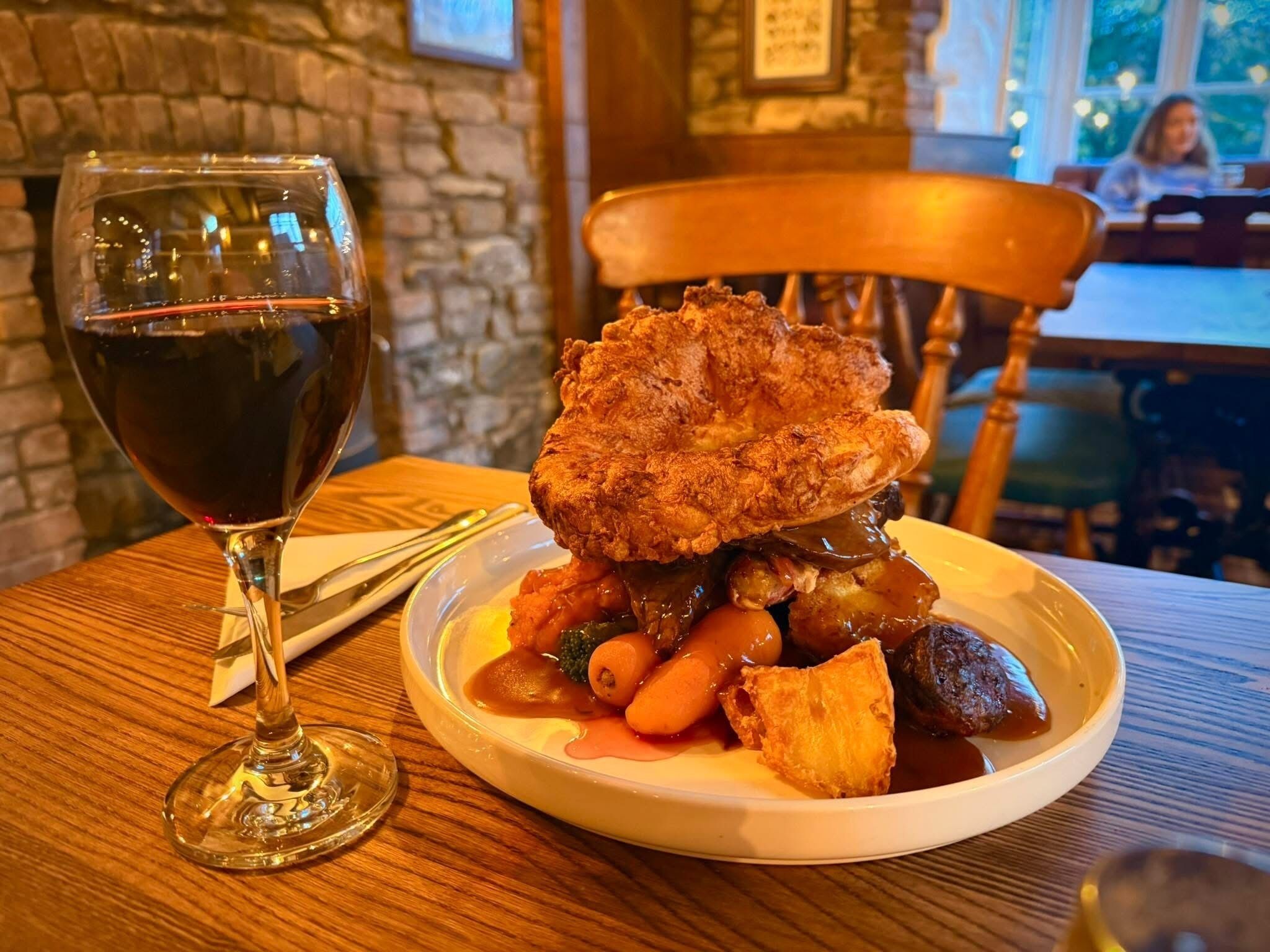 A plate of food with a glass of red wine on a wooden table.