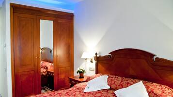 Une chambre à coucher avec une armoire en bois, une table de chevet avec une lampe et un lit avec une literie à motifs floraux.