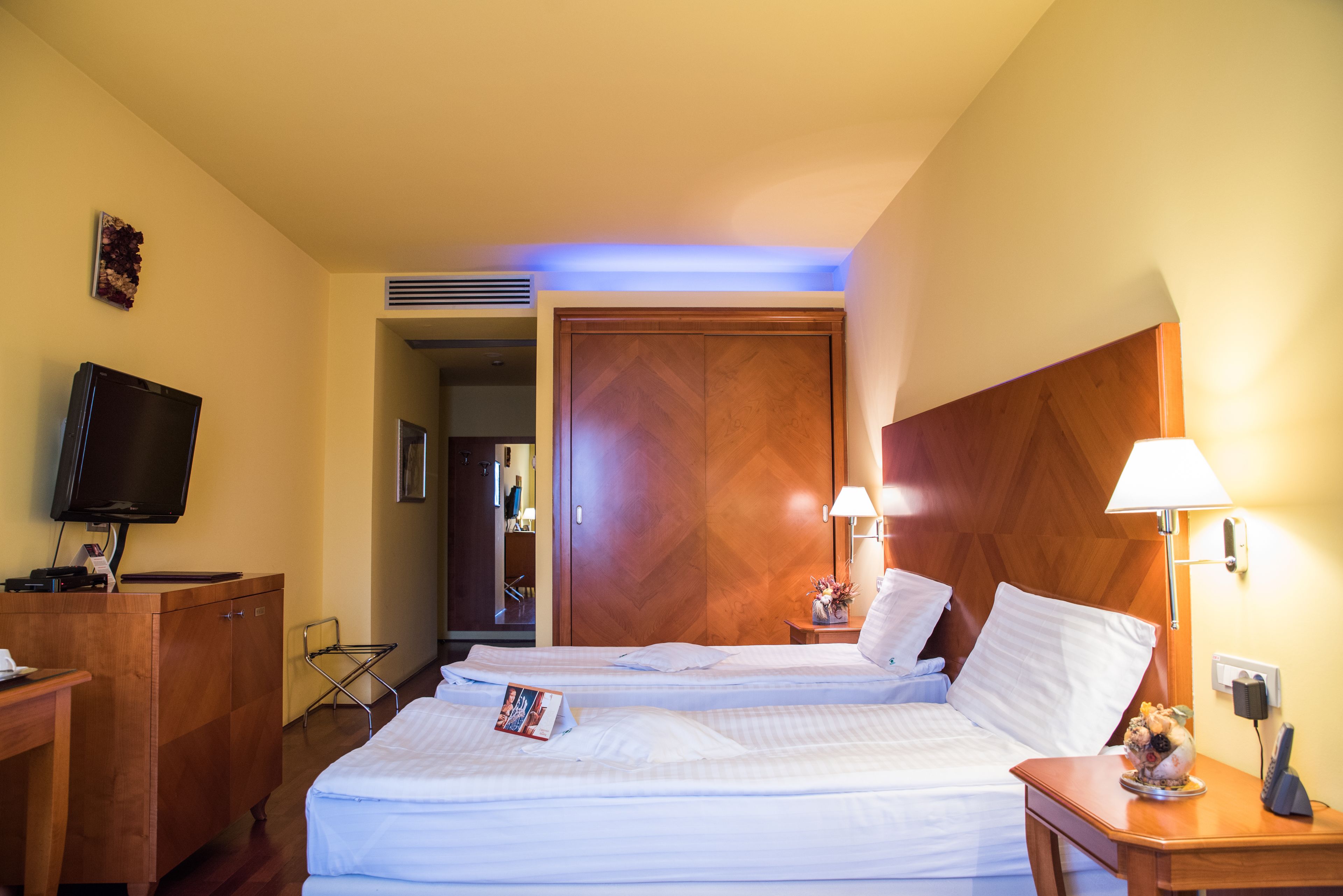 Ett hotellrum med två sängar, en TV, ett skrivbord och en lampa.