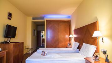 Habitación de hotel con dos camas, televisión, escritorio y lámpara.
