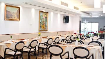 A conference room with tables set for a meeting, equipped with chairs and a projector screen.