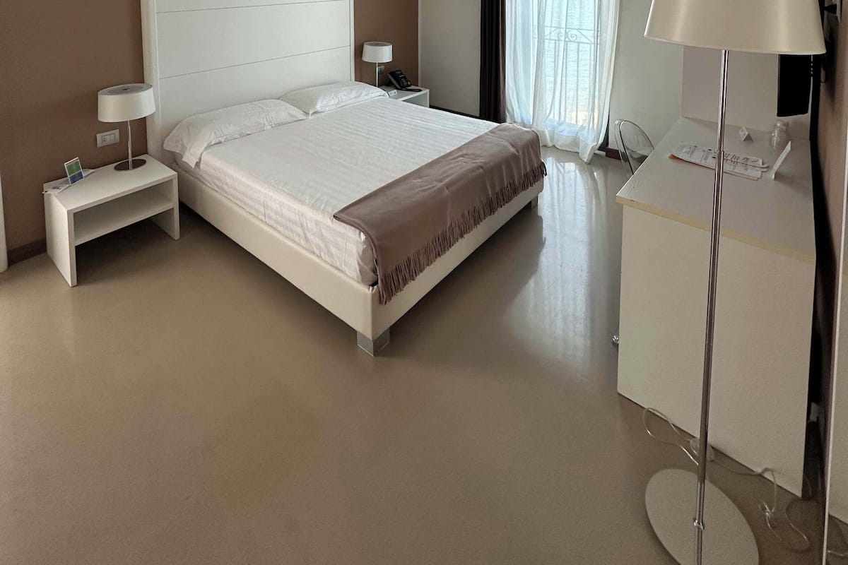 Una habitación de hotel moderna con una cama grande, mesitas de noche, un escritorio y una silla.